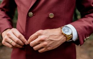 Close-up of man wearing a suit and golden watch buttoning his jacket